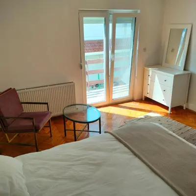 a bedroom with a bed and a chair and a glass table at Sienas Holiday Home in Vrnjačka Banja