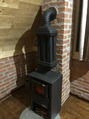 a black wood stove in a brick wall at Koliba Joca in Lepterija