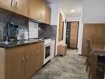 a kitchen with wooden cabinets and a table in it at MP Apartman in Soko Banja