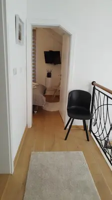 a hallway with a black chair and a living room at Royal Vila Bozovic - G5 i G6 in Vrnjačka Banja