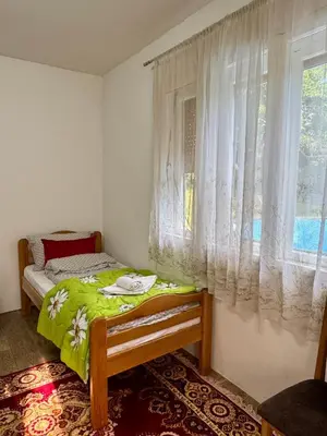 a small bedroom with a bed and a window at Idila pod Rtnjem - Najam cele vikendice sa bazenom in Ilino