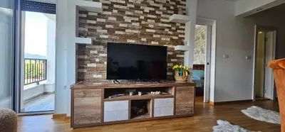 a living room with a television on a brick wall at Vrnjački Lux free parking GARAGE in Vrnjačka Banja