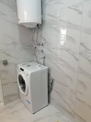 a white bathroom with a washing machine in the corner at Sunflower apartment in Niš