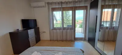 a bedroom with a bed and a tv and windows at Apartmani Talija 3 i 4 Sokobanja in Soko Banja