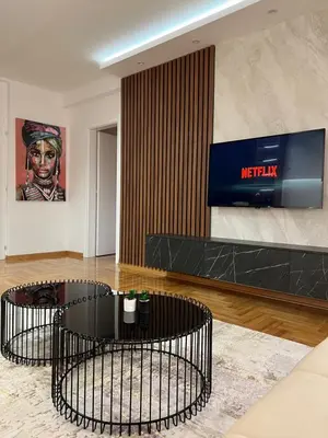 a lobby with two black tables and a television at MM LUX apartment in Niš