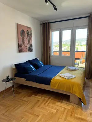 a bedroom with a bed with blue sheets and a window at MM LUX apartment in Niš