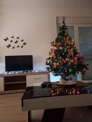 a christmas tree in a living room with a desk at Apartman Nikolic in Jagodina