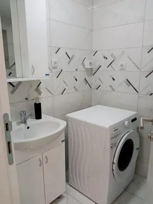 a white bathroom with a washing machine and a sink at Apartman Nikolic in Jagodina
