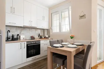 a kitchen with white cabinets and a table and chairs at Duma Apartmani 1 Vrnjačka Banja in Vrnjačka Banja