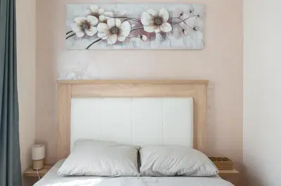 a bedroom with a bed with a painting on the wall at Duma Apartmani 1 Vrnjačka Banja in Vrnjačka Banja