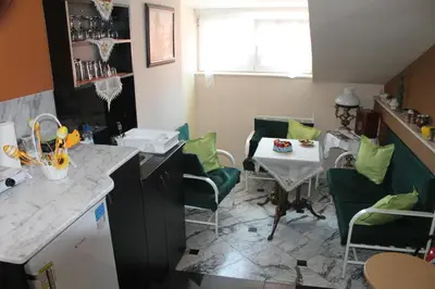 a kitchen with a table and green chairs and a table at Royal Apartments in Niš