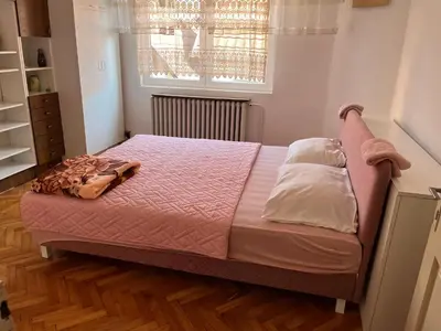 a bedroom with a bed with a pink comforter at Kobran in Kuršumlija