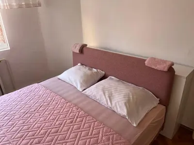 a bed with a pink headboard with two pillows at Kobran in Kuršumlija