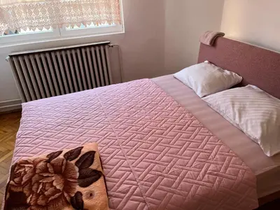 a bedroom with a bed with a pink comforter at Kobran in Kuršumlija