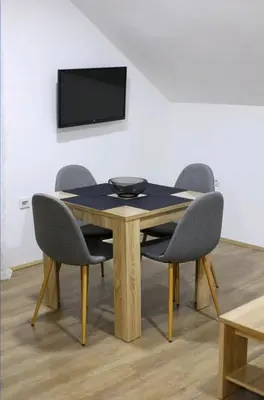 a table with four chairs and a television on a wall at Apartman Luki in Soko Banja