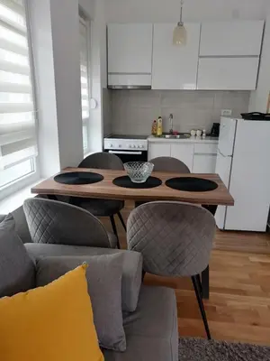 a living room with a table and chairs and a kitchen at Apartman Dolce Vita Sokobanja in Soko Banja