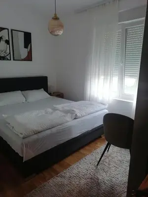 a bedroom with a bed and a chair and a window at Apartman Dolce Vita Sokobanja in Soko Banja