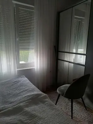 a bedroom with a bed and a chair and a window at Apartman Dolce Vita Sokobanja in Soko Banja