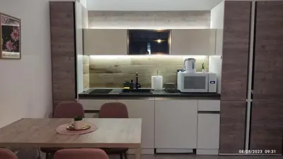 a kitchen with white cabinets and a table with a microwave at La Vie En Rose - Milmari Resort in Kopaonik