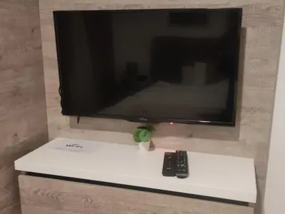 a tv on a wall with two remote controls at La Vie En Rose - Milmari Resort in Kopaonik