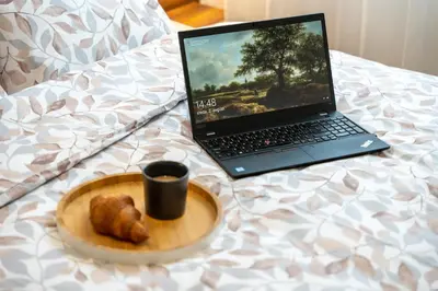 a laptop computer sitting on a bed next to a plate of food at Contigo Apartman Vrnjacka Banja - Vrnjacka promenada in Vrnjačka Banja