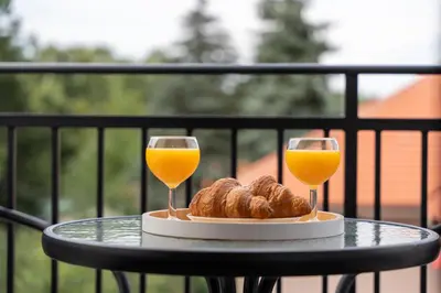 a table with two glasses of orange juice and pastries at Contigo Apartman Vrnjacka Banja - Vrnjacka promenada in Vrnjačka Banja