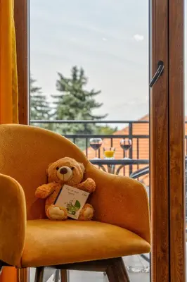 a teddy bear sitting in a chair with a book at Contigo Apartman Vrnjacka Banja - Vrnjacka promenada in Vrnjačka Banja
