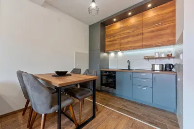 a kitchen with a wooden table and blue cabinets at Contigo Apartman Vrnjacka Banja - Vrnjacka promenada in Vrnjačka Banja