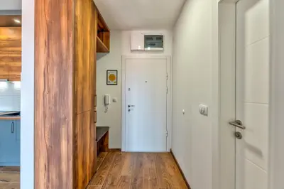 a hallway with a white door and a wooden floor at Contigo Apartman Vrnjacka Banja - Vrnjacka promenada in Vrnjačka Banja