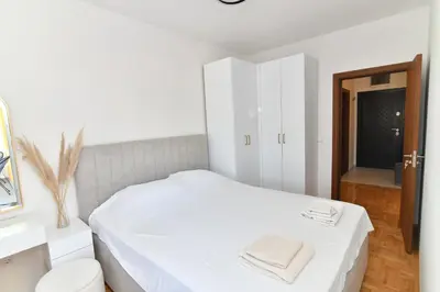 a small bedroom with a white bed and a mirror at Apartman Dina in Pirot