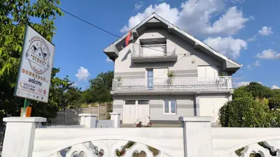 a white house with a balcony and a sign at Domaćinsvo Stević - Sekurič in Belušić
