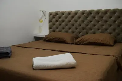 a bed with a large headboard with a white towel on it at Skandik Luxe Residence in Jagodina