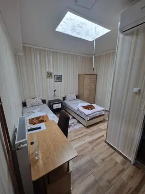 a room with two beds and a table and a skylight at Hotel Saradis in Kruševac