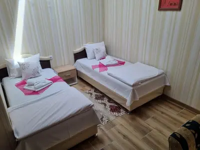 two beds in a hotel room with pink sheets at Hotel Saradis in Kruševac