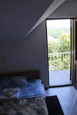 a bedroom with a bed and a sliding glass door at Apartman Denčić Zavojsko jezero in Pirot
