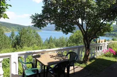 a table and chairs on a balcony with a view of a lake at Apartman Denčić Zavojsko jezero in Pirot