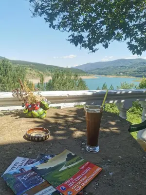 a drink on a table with a view of a lake at Apartman Denčić Zavojsko jezero in Pirot