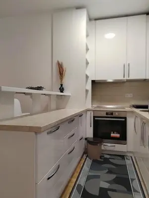 a kitchen with white cabinets and a black and white floor at Apartman Mančić in Pirot