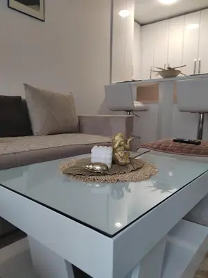 a living room with a glass coffee table with a statue on it at Apartman Mančić in Pirot