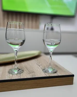 two wine glasses sitting on top of a wooden board at apartman gold Jagodina in Jagodina