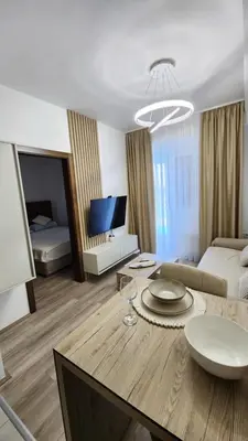 a living room with a table and a room with a bed at apartman gold Jagodina in Jagodina