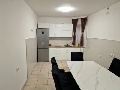 a kitchen with a table and chairs and a refrigerator at Hedonic Wellness Apartmani in Niš