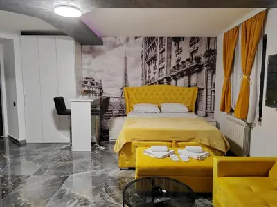 a bedroom with a yellow bed and a desk at Hedonic Wellness Apartmani in Niš