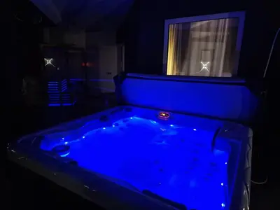 a blue tub in a dark room with a window at Hedonic Wellness Apartmani in Niš