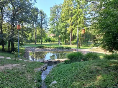 a pond in a park with trees and grass at Tilia Home in Vrnjačka Banja