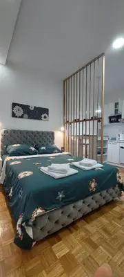 a bedroom with a large bed with a green blanket at AIK Kula studio in Jagodina