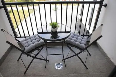 a glass table and chairs with a potted plant on a balcony at Apartman Ruby in Vrnjačka Banja