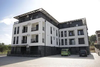 a white building with cars parked in front of it at Apartman Ruby in Vrnjačka Banja
