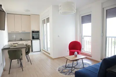 a kitchen and living room with a red chair and a table at Apartman Ruby in Vrnjačka Banja