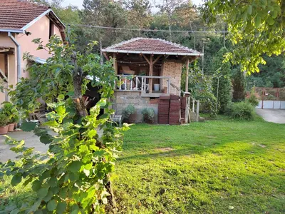 a small house with a porch in a yard at IKONIJA guest house in Pečenjevce